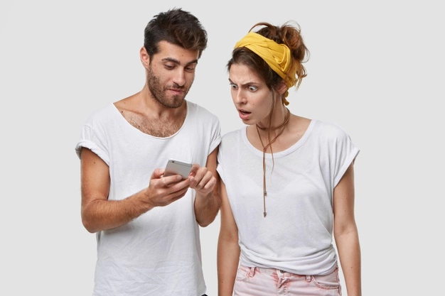 גבר ואישה עומדים יחד, מסתכלים בטלפון הנייד.